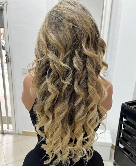 Melena larga con balayage rubio y ondas suaves en Peluquería América